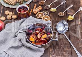 mulled wine in a saucepan and iron spoons with ingredients