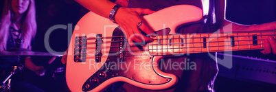 Female guitarist playing guitar with drummer in nightclub