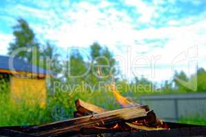 firewood burning on blue sky background in summer
