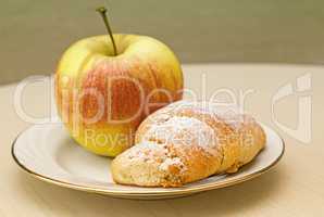 Cake and Apple on the table on a plate.