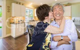 Happy Senior Chinese Couple Kissing Inside Beautiful Custom Kitc