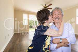 Happy Senior Chinese Couple Kissing Inside Empty Room Of New Hou