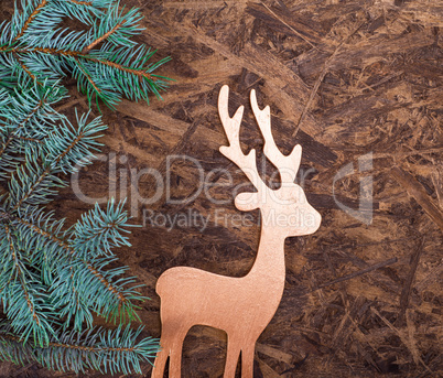 A wooden background with a green spruce branch and a wooden toy