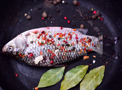 fresh fish with spices in a black frying pan