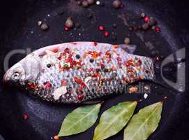 fresh fish with spices in a black frying pan