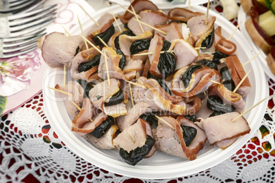 Snack: ham and prunes in thin sticks on the plate.