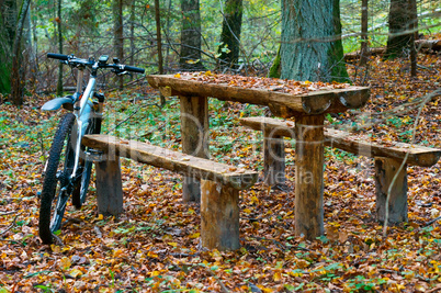bike around a wooden table with benches in the woods