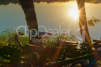 the bike in the sun camping, the sunset, the sun reflected in the water, the sun breaks through the trees