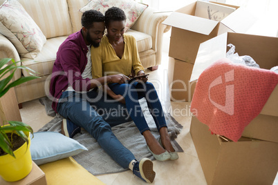 Couple using digital tablet while relaxing in new house