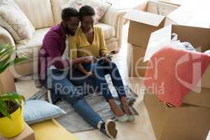 Couple using digital tablet while relaxing in new house