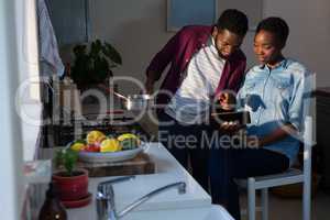 Couple using digital tablet while cooking