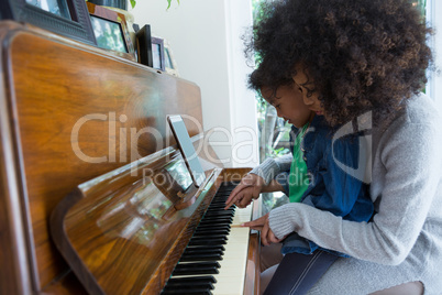 Mother assisting daughter in playing piano