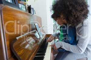 Mother assisting daughter in playing piano