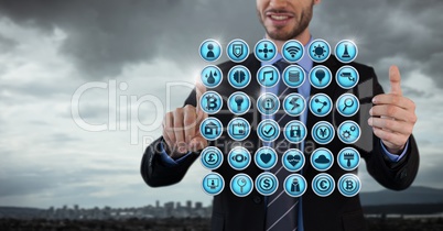 Various app icons rowed and Businessman with hands touching air in city office