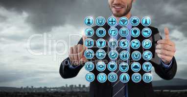 Various app icons rowed and Businessman with hands touching air in city office