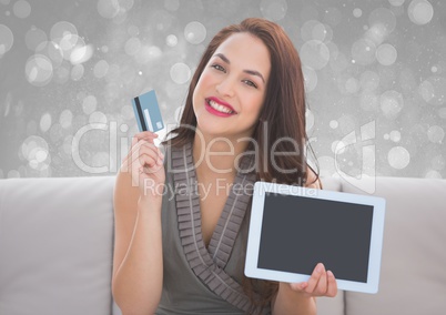 woman holding bank card and tablet on couch