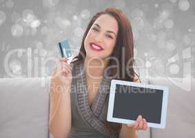 woman holding bank card and tablet on couch