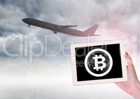 Airplane and Bitcoin icon on tablet in hand