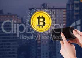 Bitcoin icon next to hand holding phone