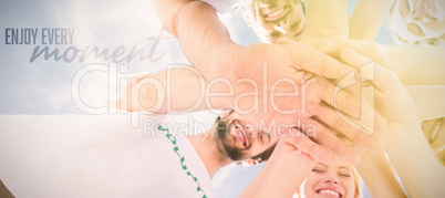 Composite image of happy volunteers with hands together against blue sky