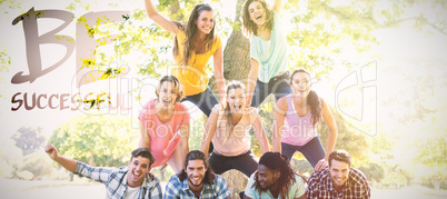 Composite image of happy friends in the park making human pyramid