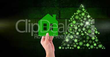 Hand holding home and Snowflake Christmas tree pattern shape glowing green