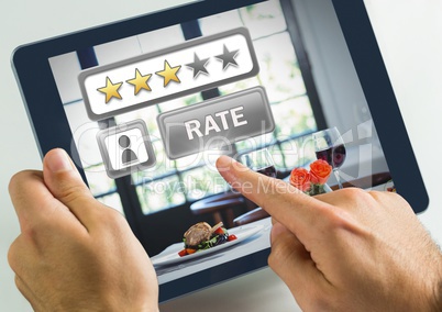 Hand touching tablet with Rate button and review stars in restaurant with dinner food