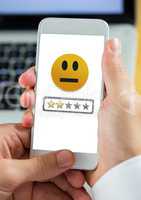 Hand holding phone with medium satisfaction smiley face and star ratings review feedback
