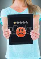 Woman holding tablet with one star rating and sad smiley face