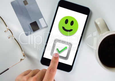 Hand touching correct tick and smiley face on phone