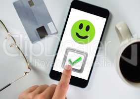 Hand touching correct tick and smiley face on phone
