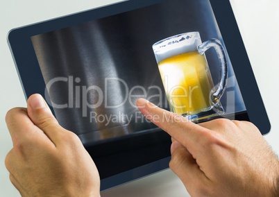 Hand touching tablet with beer in bar