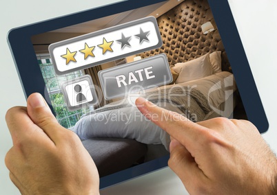 Hand touching tablet with Rate button and review stars in hotel bedroom