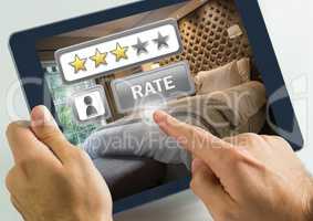 Hand touching tablet with Rate button and review stars in hotel bedroom