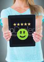 Woman holding tablet with smiley face and five star review