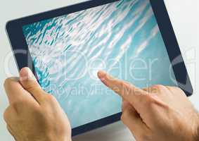 Hand touching tablet with water in swimming pool