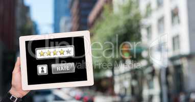 Hand holding tablet with Rate button and star ratings review icons in city