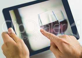 Hand touching tablet with wine glasses