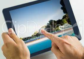Hand touching tablet with swimming pool