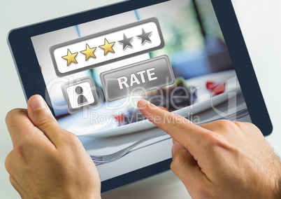 Hand touching tablet with Rate button and review stars in restaurant with dinner food