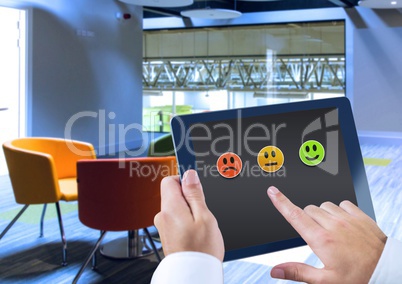 Hand holding tablet with feedback satisfaction smiley icons