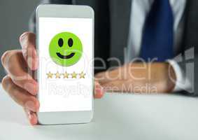 Hand holding phone with smiley face and 5 star feedback review rating