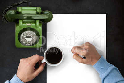 Man writing on paper while drinking coffee