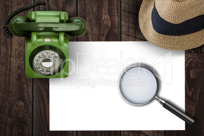 Magnifying glass on paper on side of brown hat and green phone