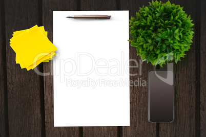 Paper on table in front of plant and smartphone