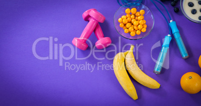Food with exercise equipment against purple background