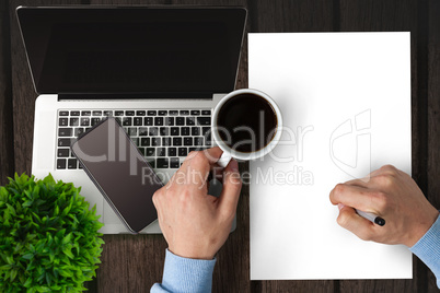 Man writing on paper while drinking coffee