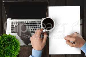 Man writing on paper while drinking coffee