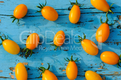 Yellow small tomatoes on blue wooden surface. top view.
