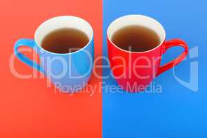 Cups with tea on a red and blue background.